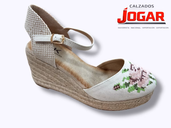 Alpargata de cuña media en yute natural con puntera de lona en tono luminoso, decorada con bordado floral artesanal en punto de cruz, talonera de tejido rústico y cierre de pulsera con hebilla.