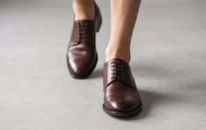 Primer plano de zapatos de piel artesanales sobre superficie neutra que resalta los acabados y costuras.